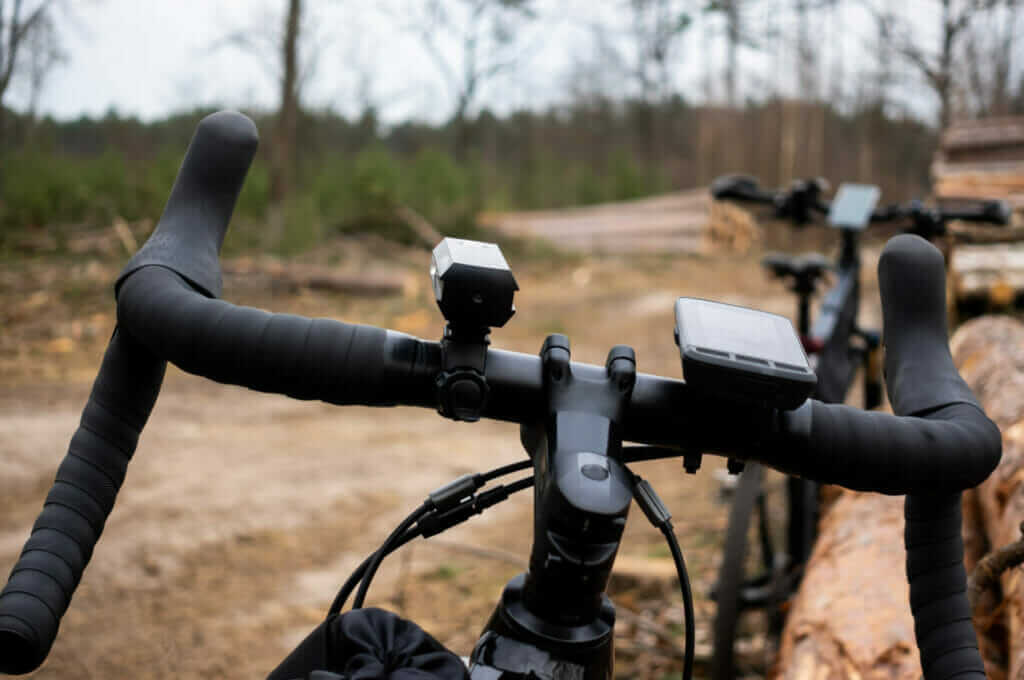 The handlebars of a bicycle with logs in the background.