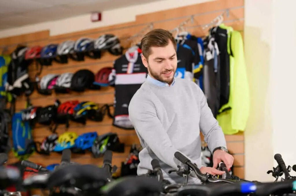 A man in a bike shop looking at bicycles.
