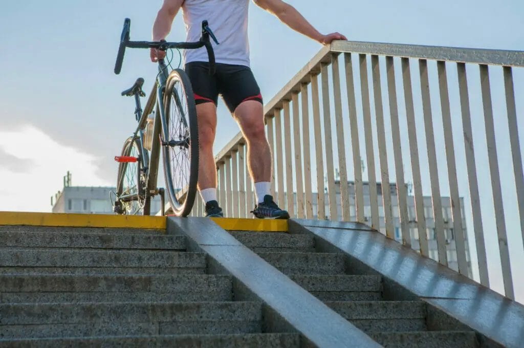 A man with a bike on a set of stairs.