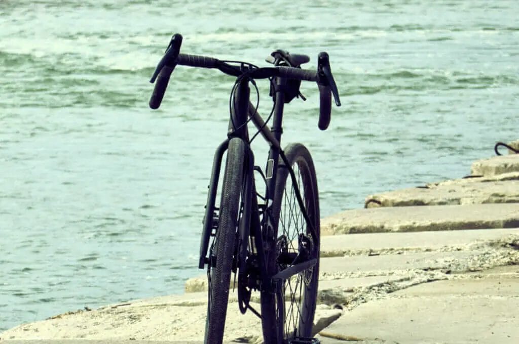 A bike leaning against a wall next to a body of water.