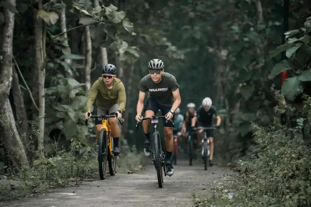 A group of mountain bikers riding down a path in the woods.