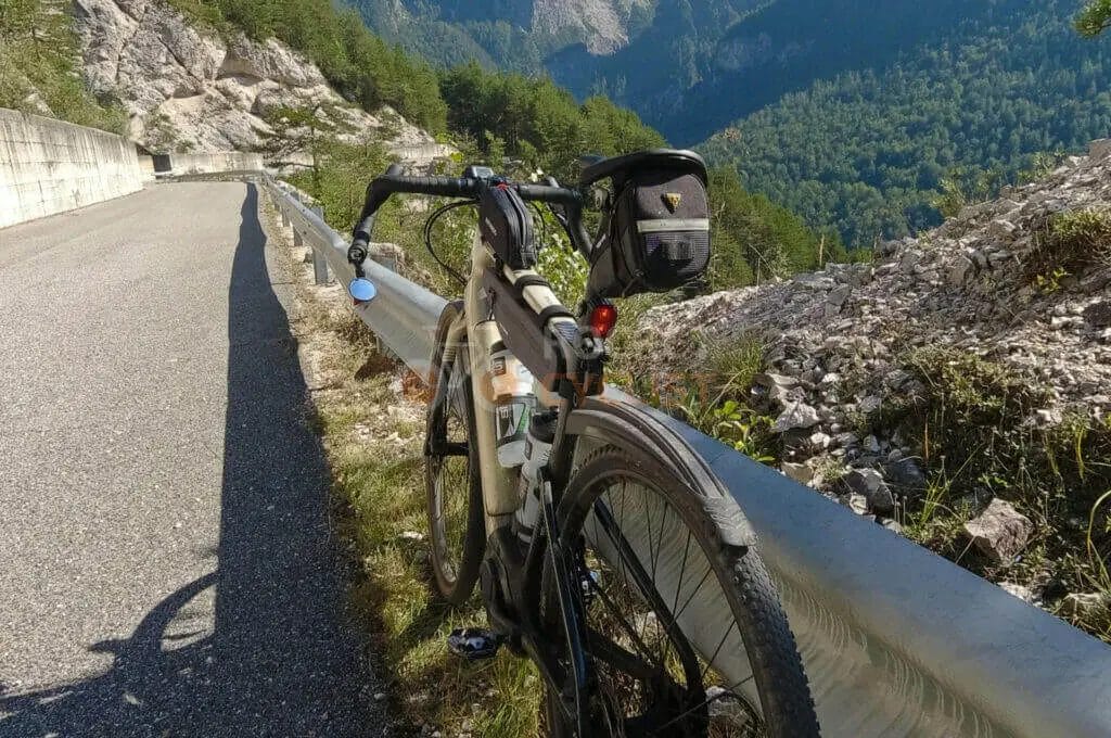 A bicycle parked by the roadside with a scenic mountain landscape in the background.