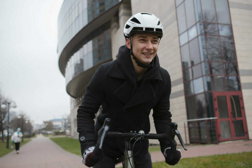 A young man riding a bicycle in front of a building.