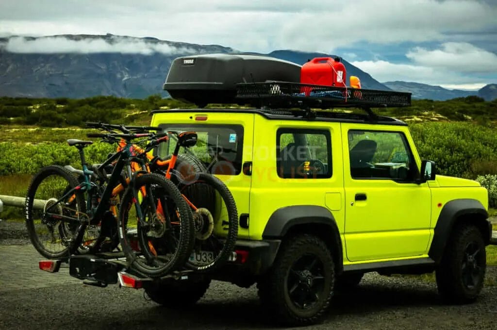A yellow suv with bicycles on the back of it.