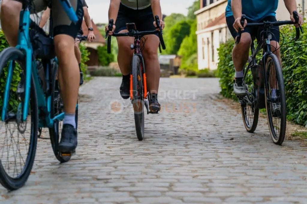 A group of people riding bicycles on a cobblestone road.