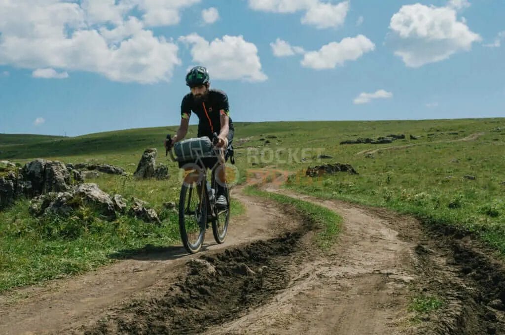 A man riding a bike on a dirt road.