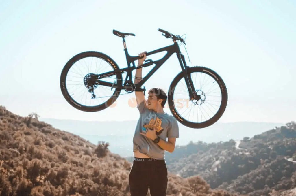 A man holding his mountain bike up in the air.