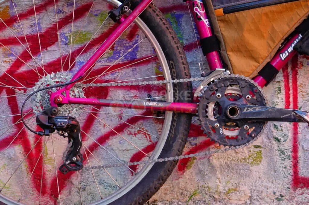 A pink bicycle leaning against a wall.