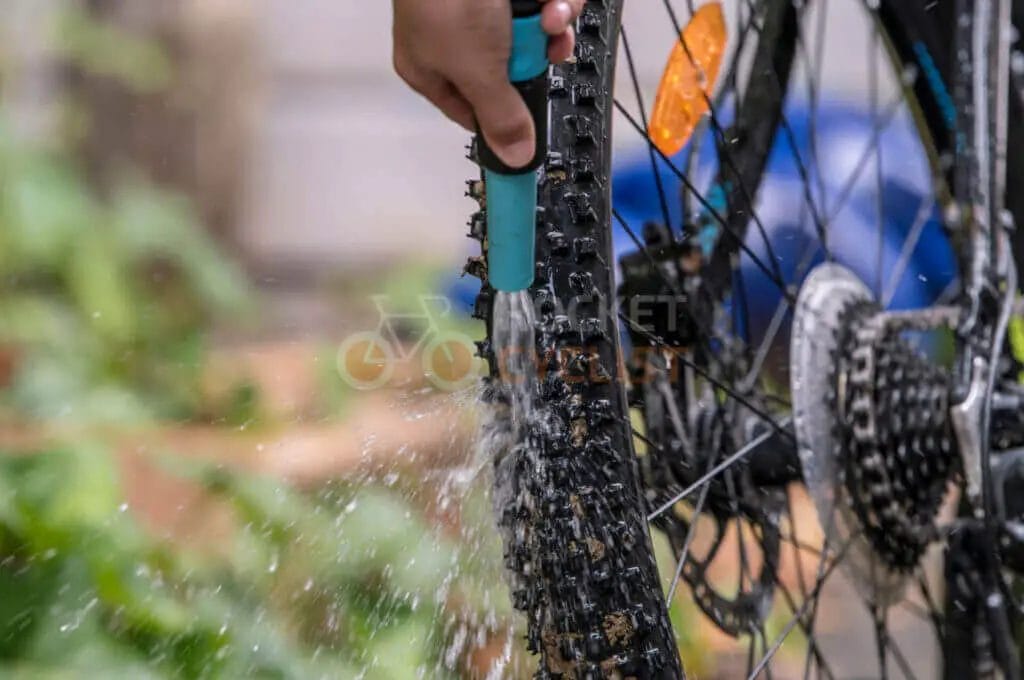 Hand washing a bicycle's gear cogs with a jet of water.