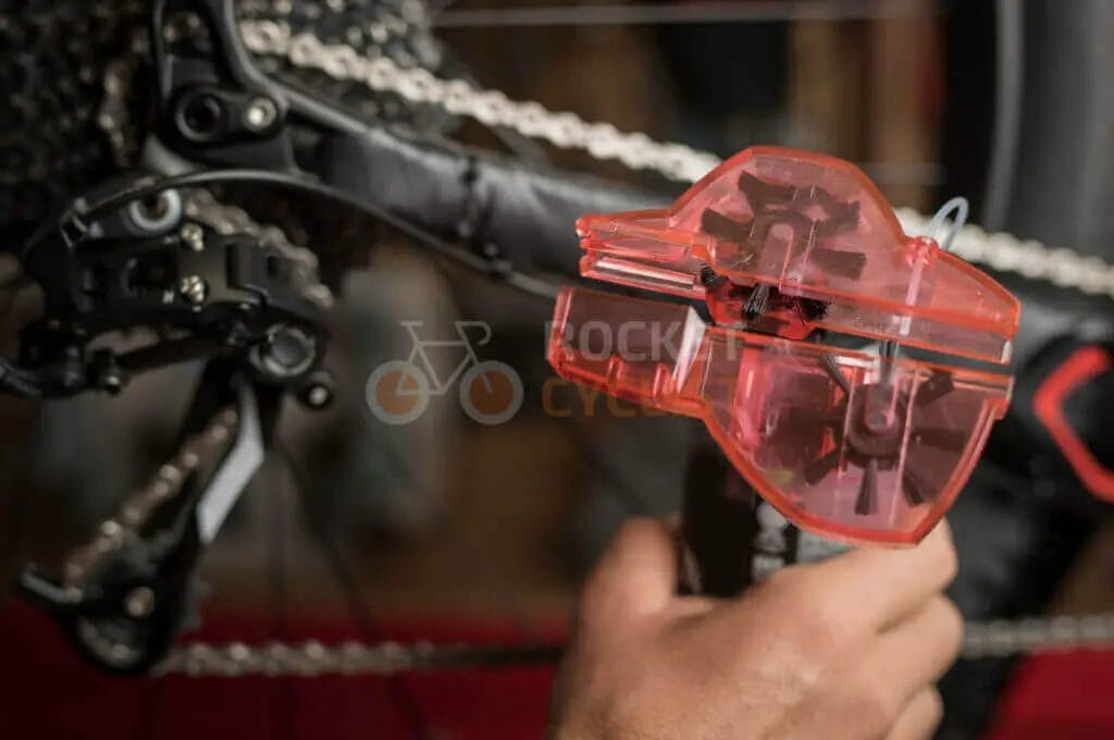 A person tuning a bicycle's gear system with a chain checker tool.