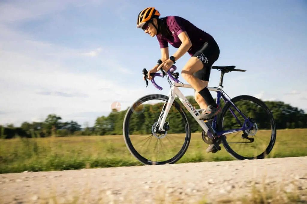 A woman riding a bike on a dirt road.