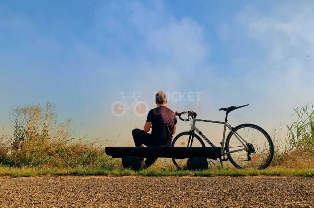 A man sitting on a bench with a bicycle.