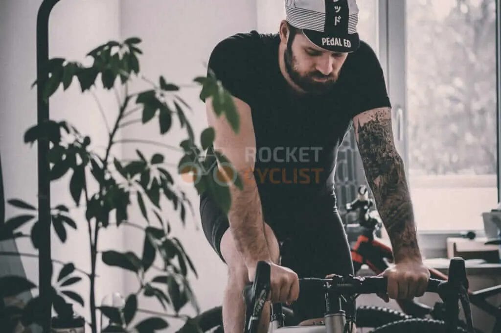 A man with tattoos riding a bike in a room.