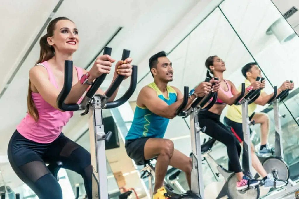 A group of people riding stationary bikes in a gym.
