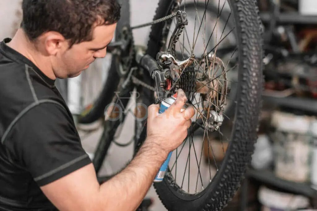 Man repairing a bicycle's rear derailleur.