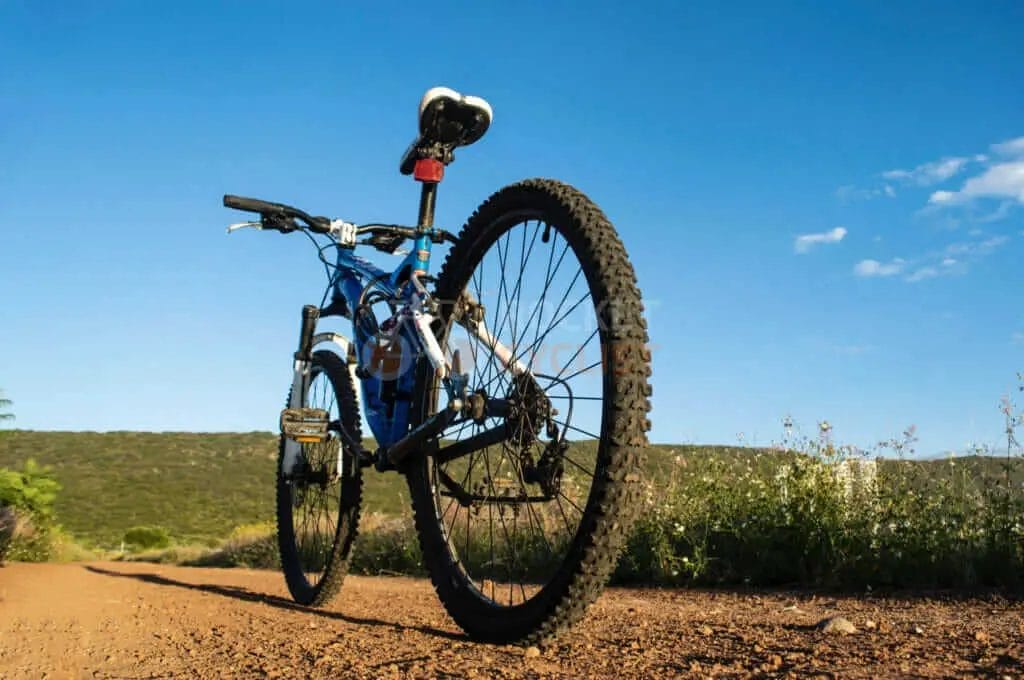 A mountain bike is parked on a dirt road.