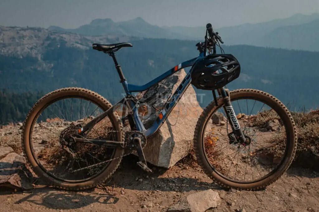 A mountain bike leaning against a rock in the mountains.