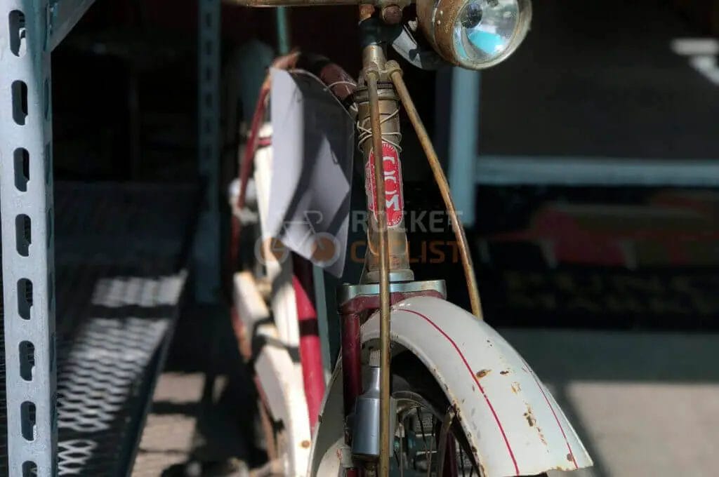 Vintage bicycle with a headlamp parked beside a metal structure.