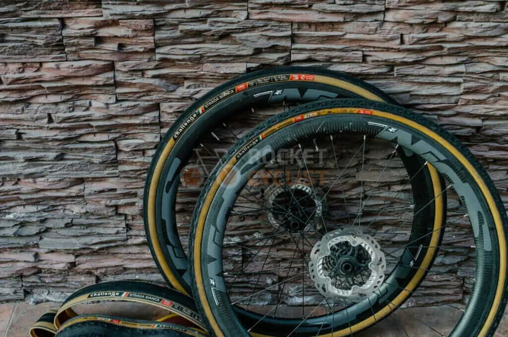 Two bicycle tires leaning against a stone wall.