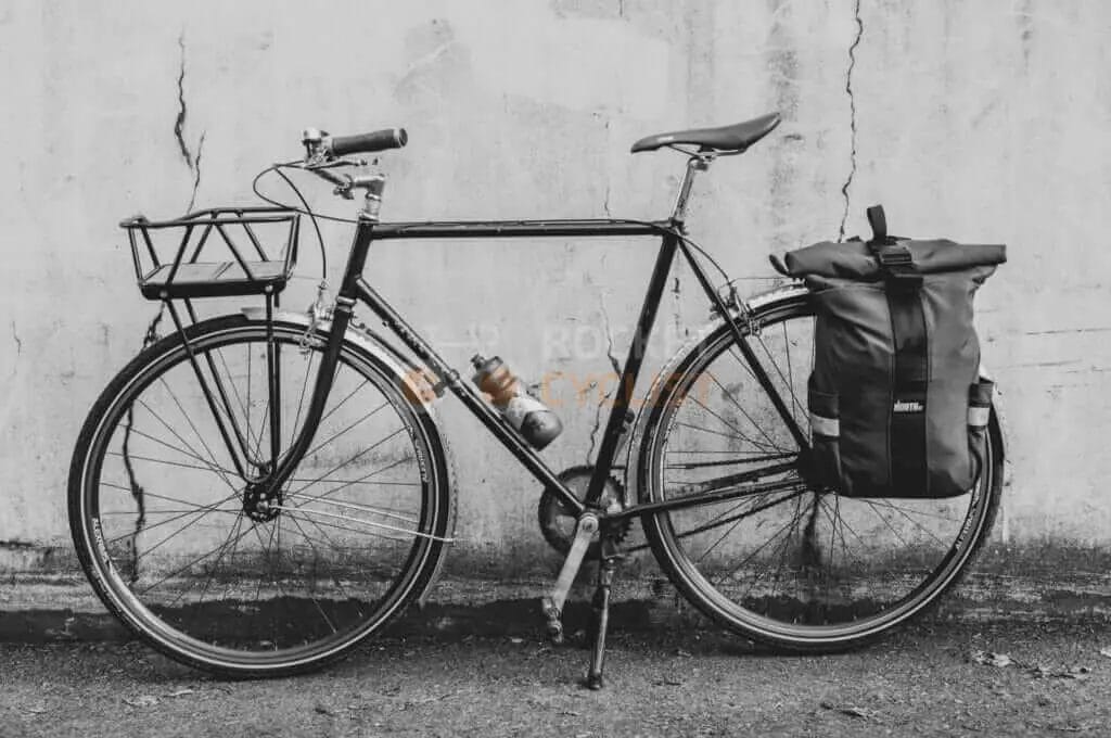 A black and white photo of a bicycle leaning against a wall.