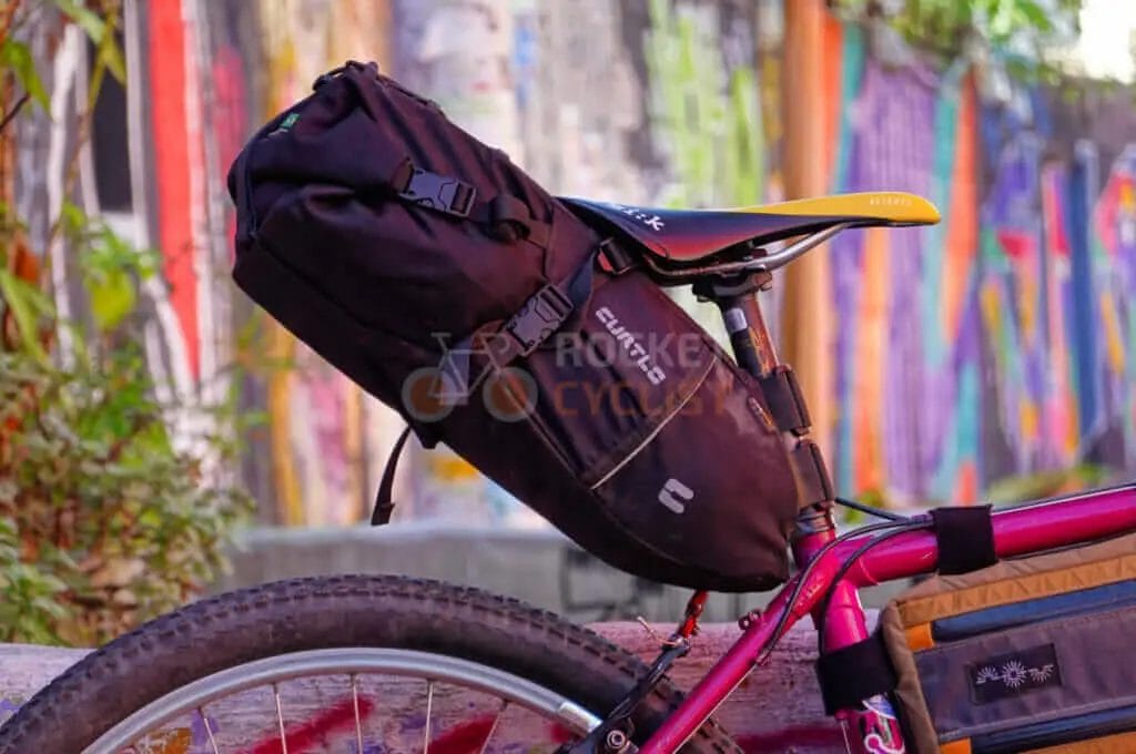 A bike with a saddle bag parked in front of a graffiti wall.