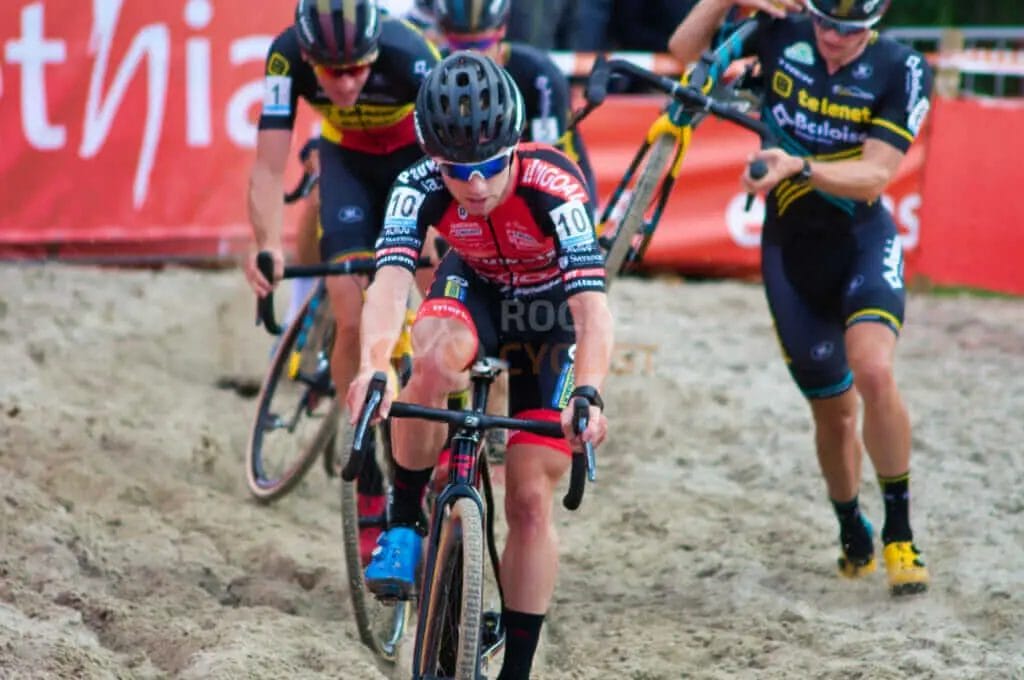 A group of cyclists racing in the sand.