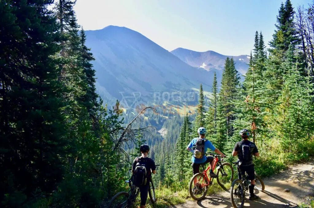 Three mountain bikers on a trail in the mountains.