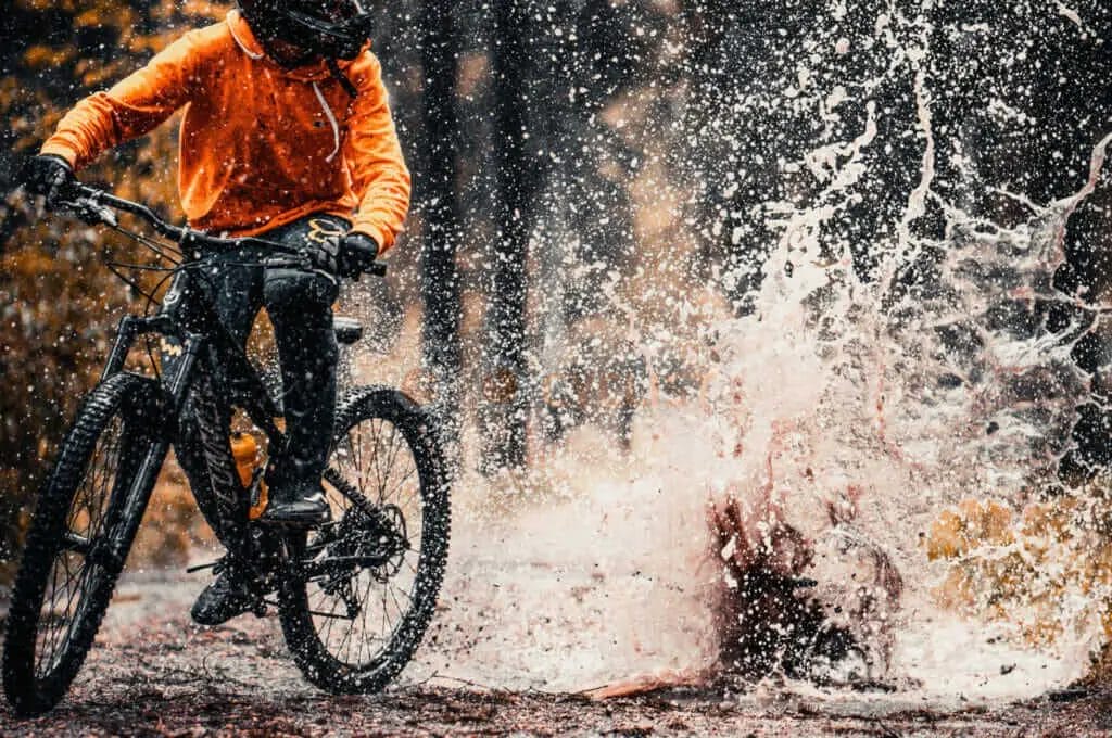 A person riding a bike through a puddle of water.