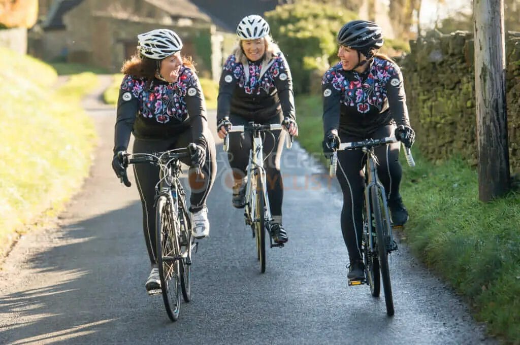 Three women riding bikes down a country road.