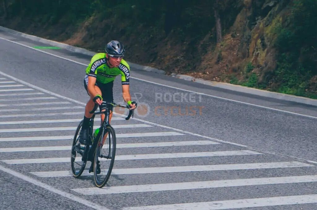 A cyclist riding down a road with a crosswalk.