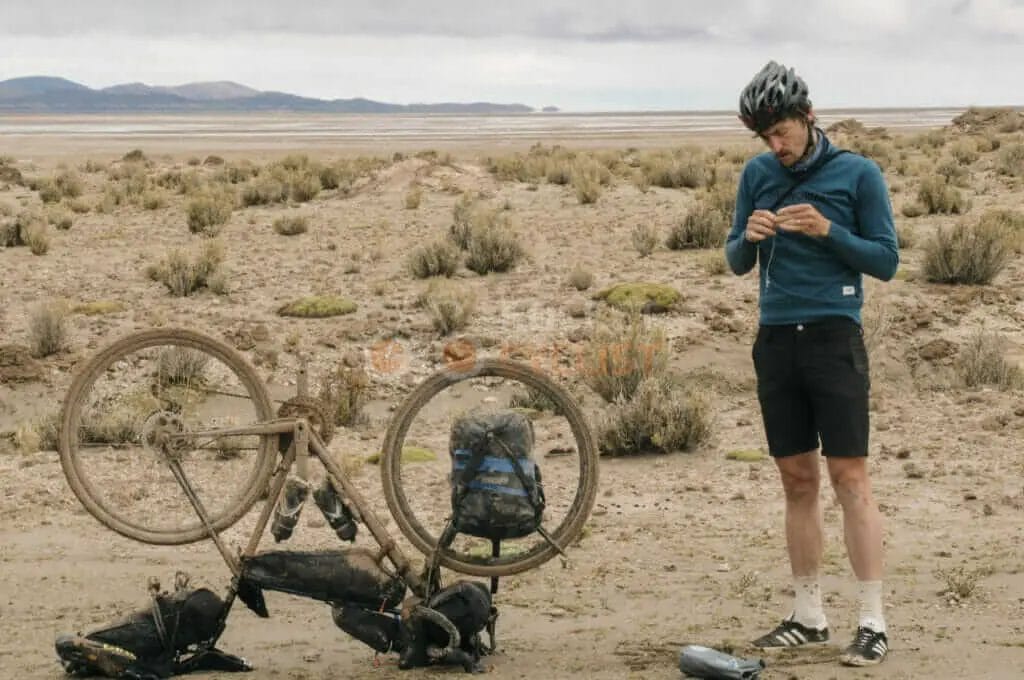 A man standing next to a bicycle in the desert.