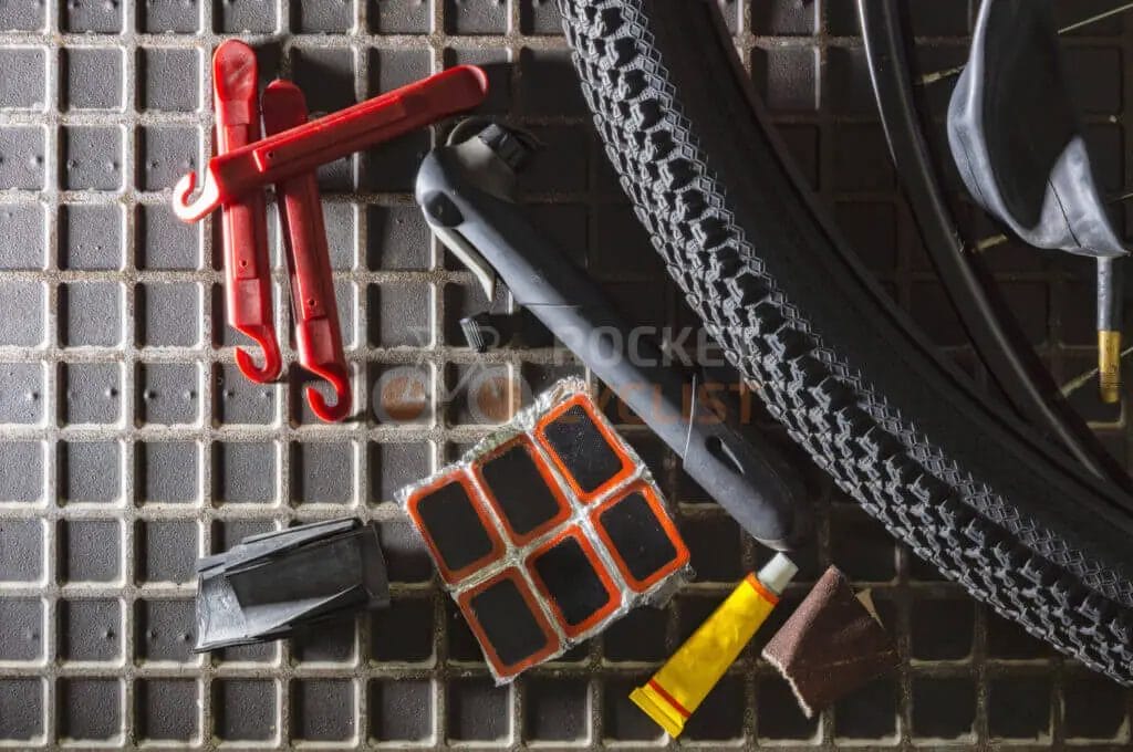 A bicycle tire and tools on a tiled floor.
