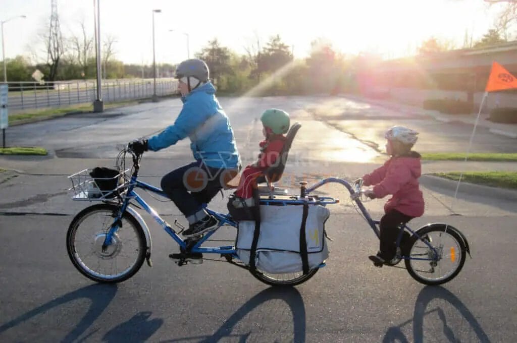 A man and a woman riding a bike with a child in a basket.