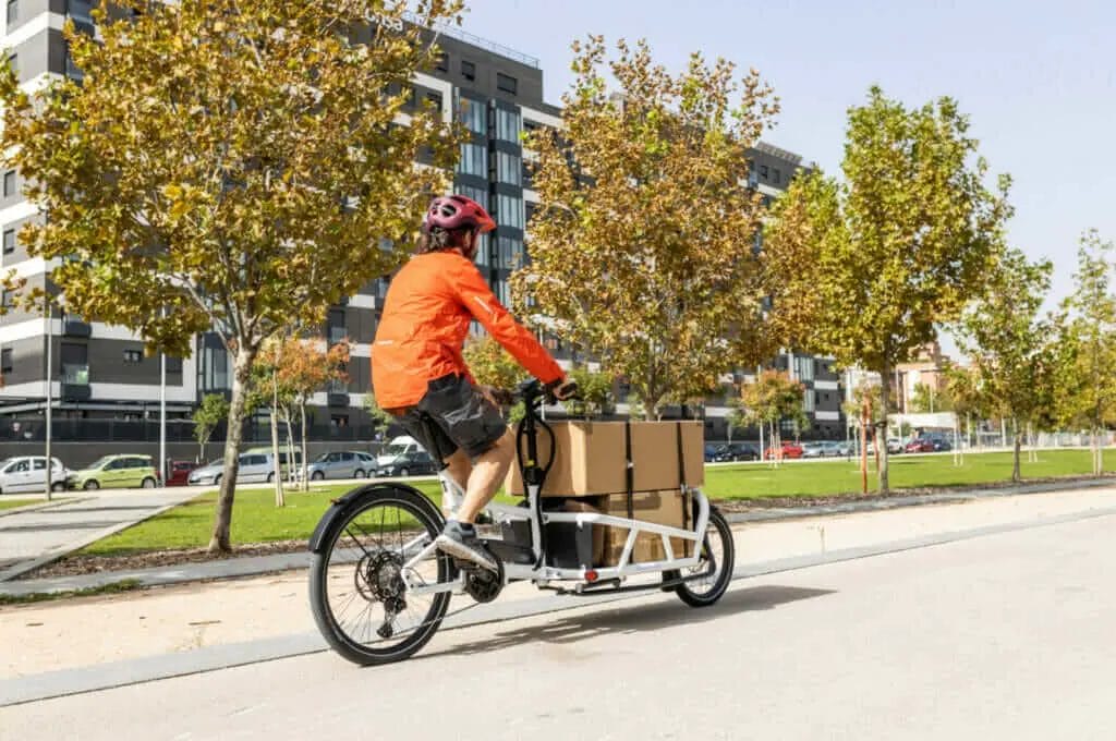 A man riding a bike with boxes on it.