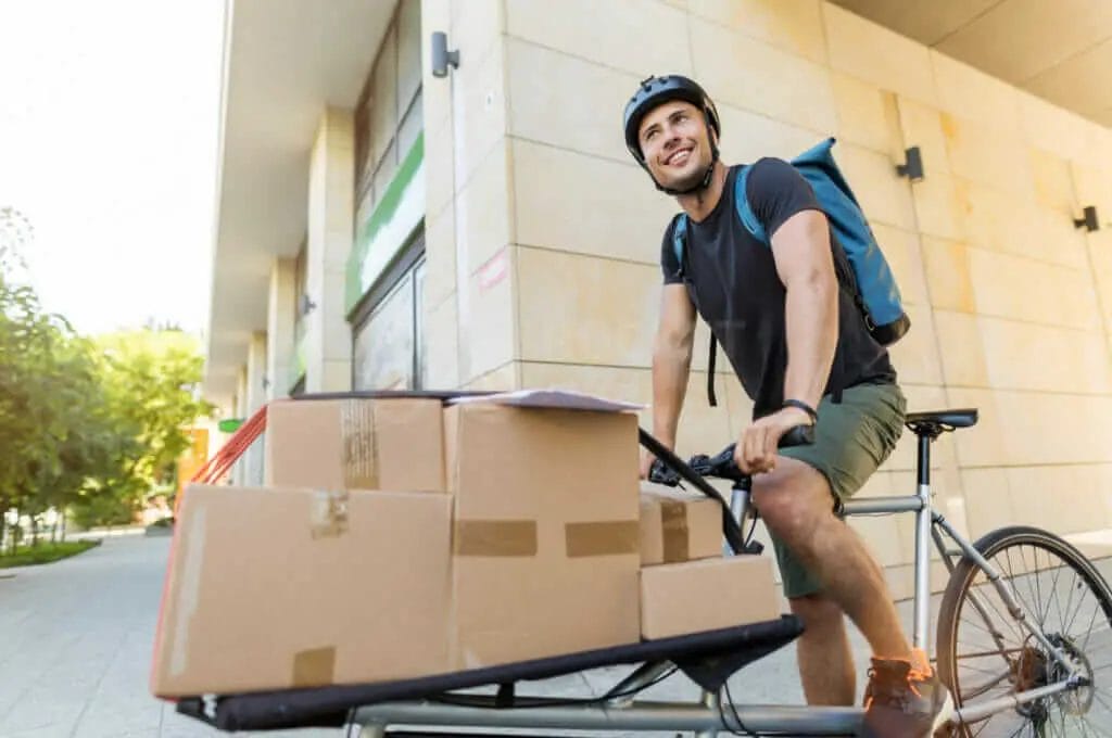 A man is riding a bicycle with boxes on it.