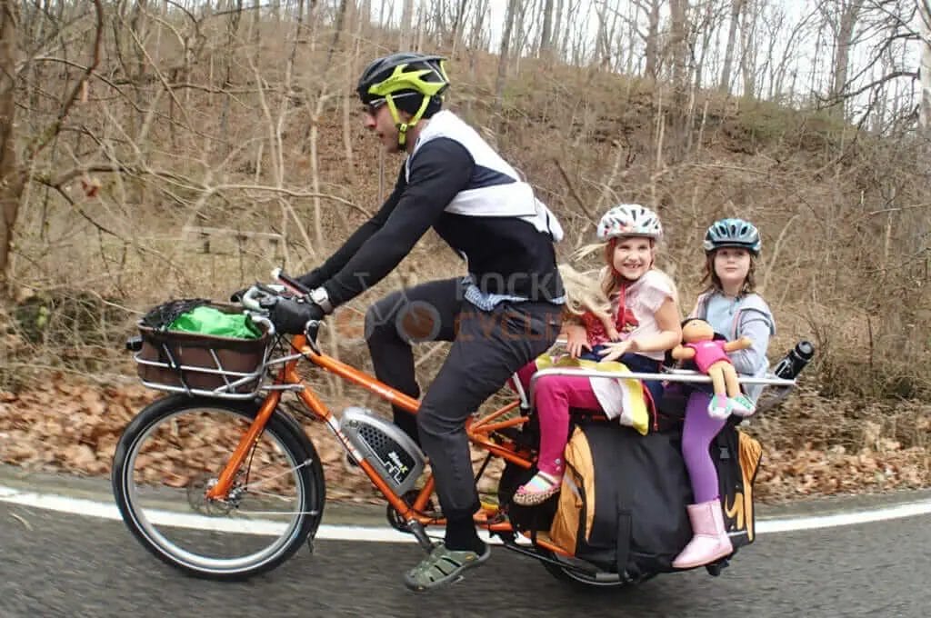 A man riding a bike with his children on the back.