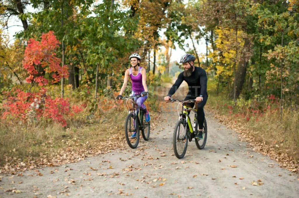 Two people riding bikes on a trail in the fall.