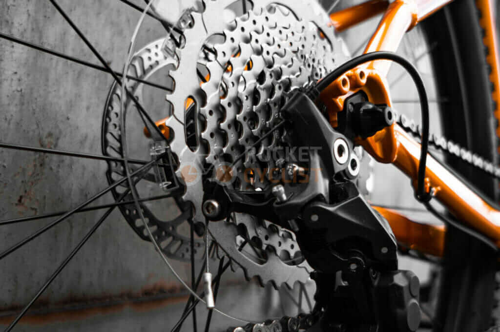 A close up of an orange bicycle with gears.
