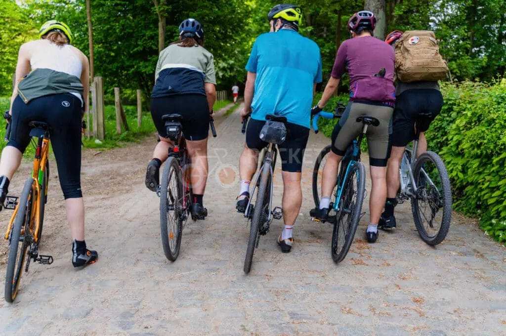 A group of people riding bikes on a cobbled path.