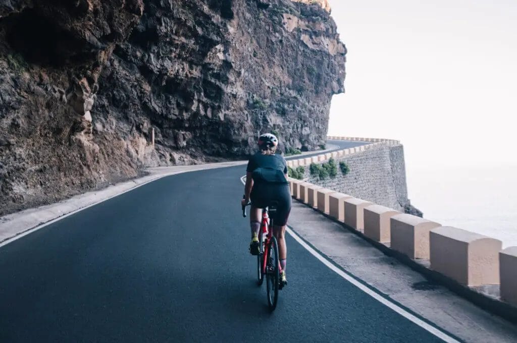 A cyclist riding down a mountain road near the ocean.