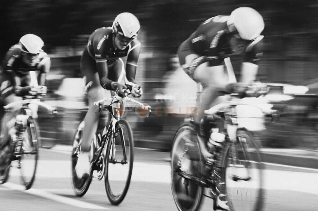 A black and white photo of a group of cyclists racing.
