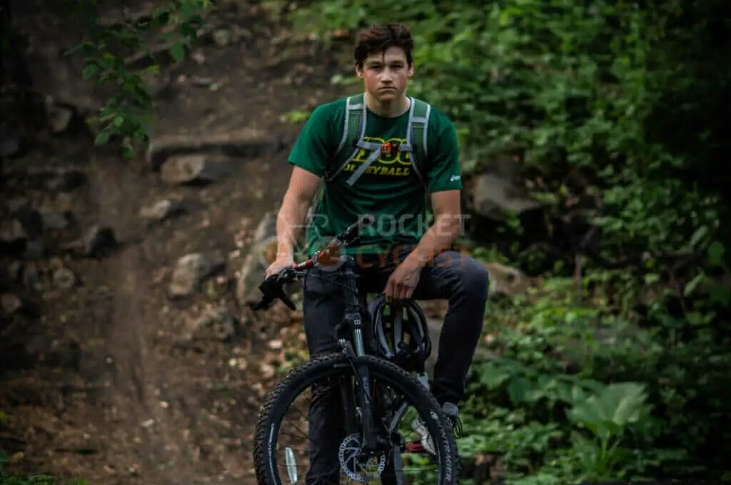 A young man on a mountain bike in the woods.