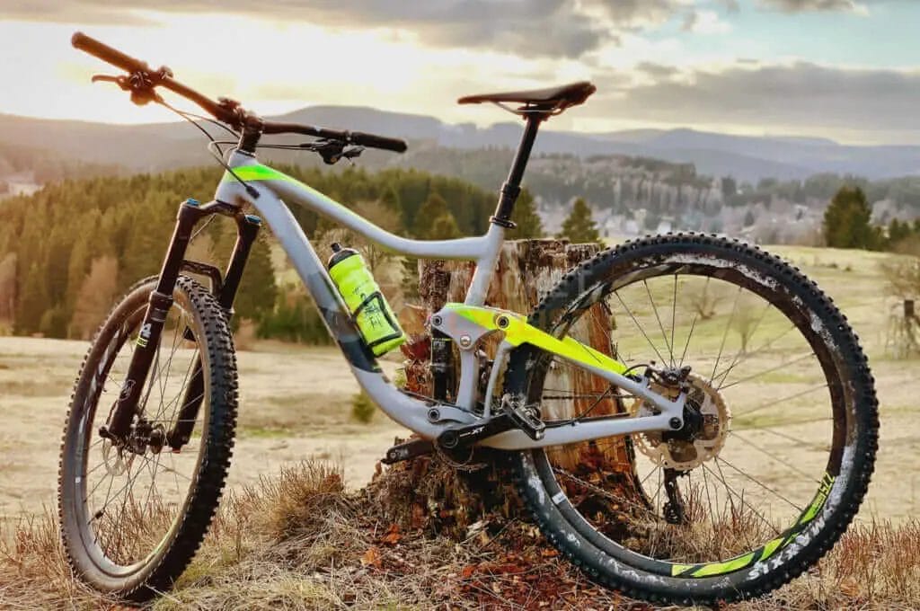 A mountain bike leaning against a tree stump.