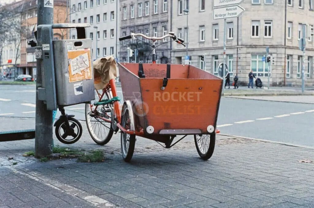 A bicycle is parked next to a meter on a city street.