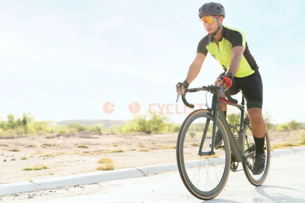 A man riding a bicycle on a desert road.