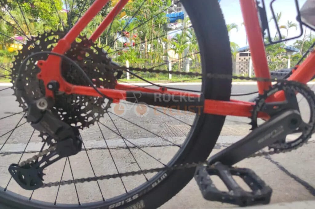 A close up of a red bicycle with a chain and gears.