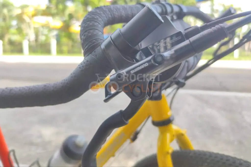 A close up of the handlebar of a yellow bicycle.