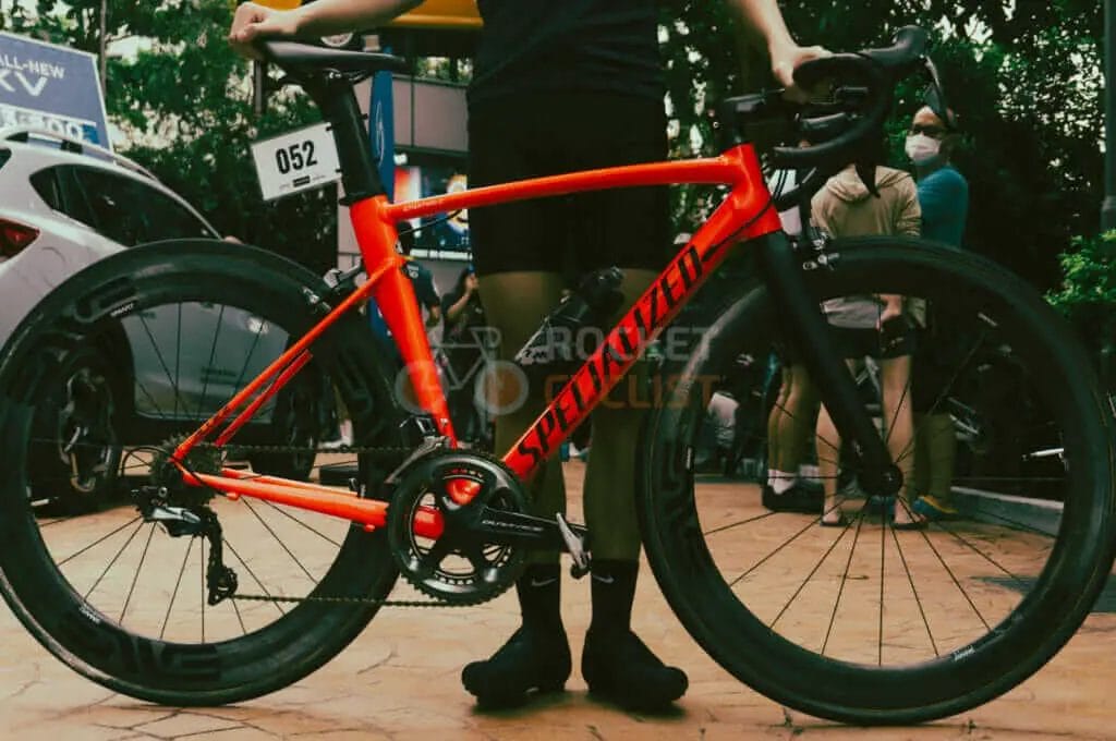 A man is standing next to a red bike.