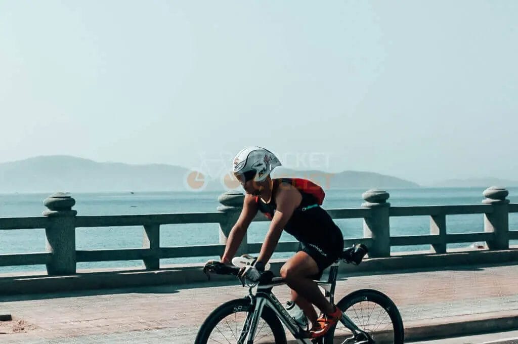 A person riding a bike on a bridge near the ocean.