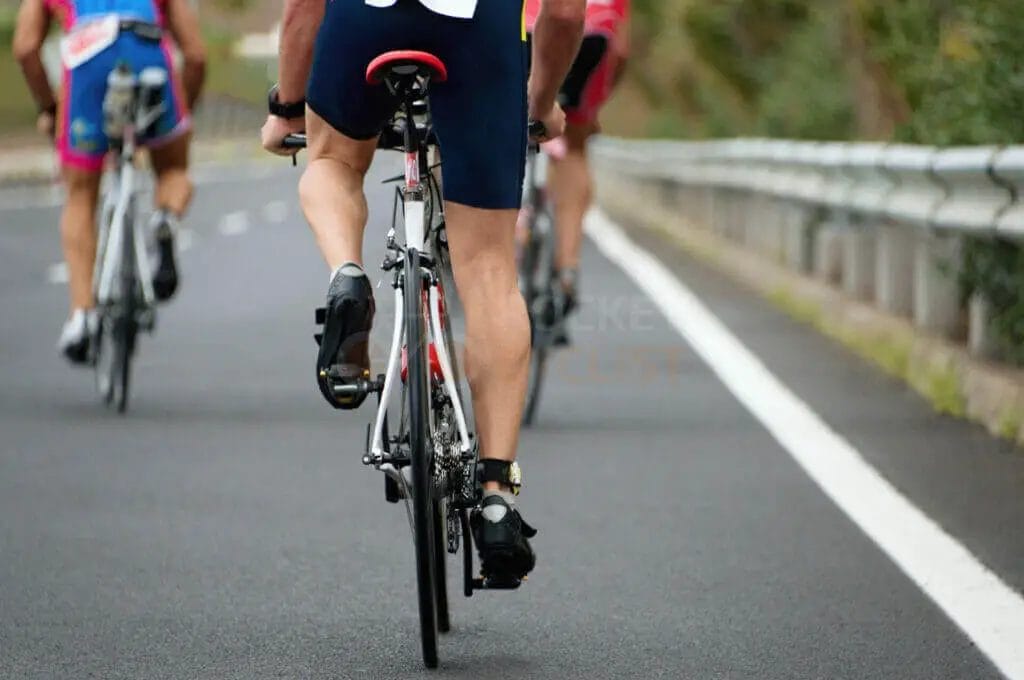 A group of bicyclists riding down a road.